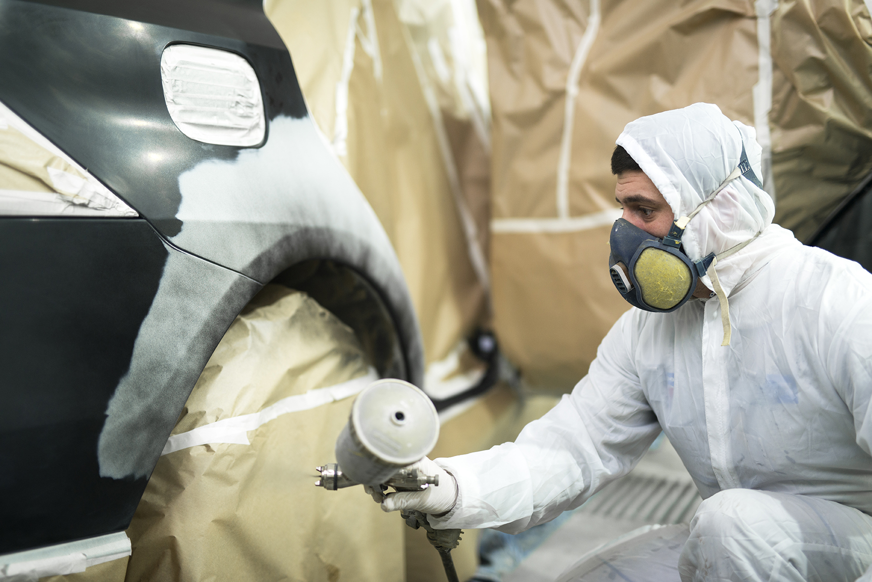 Man with protective clothes and mask painting automobile car bum